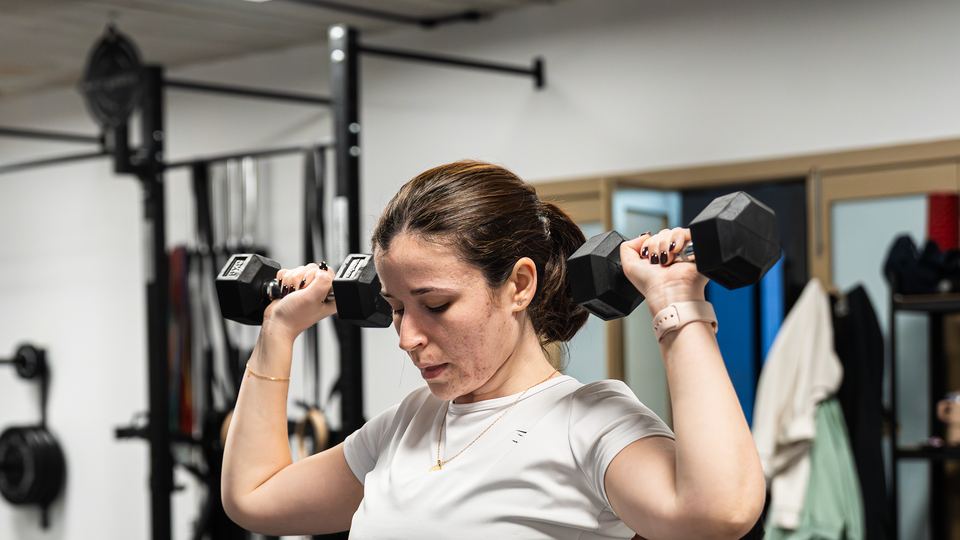 Member pressing dumbbells in a personal training session
